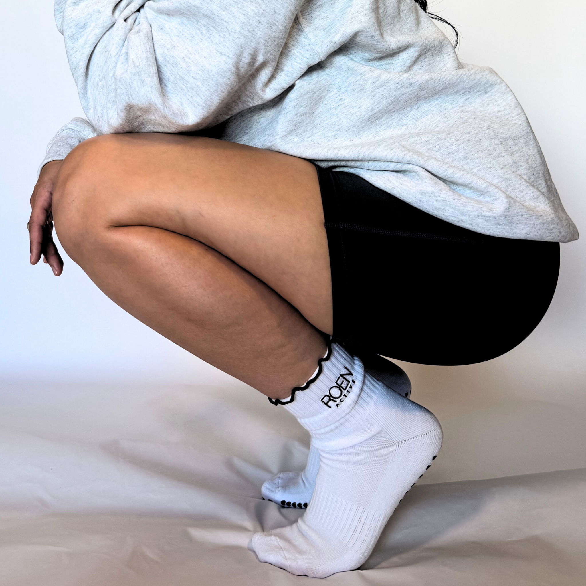 Person wearing white socks with text, sitting on a white surface.