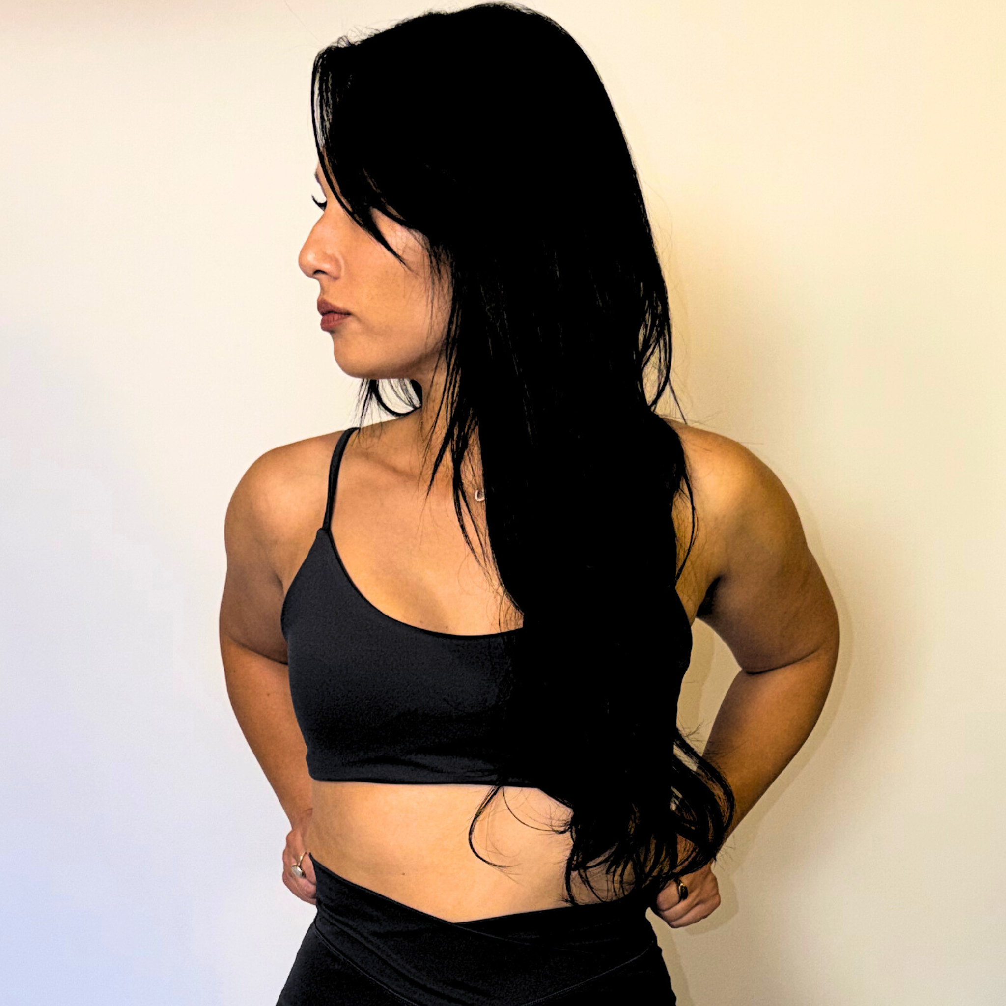Woman wearing a black sports bra and leggings against a plain background