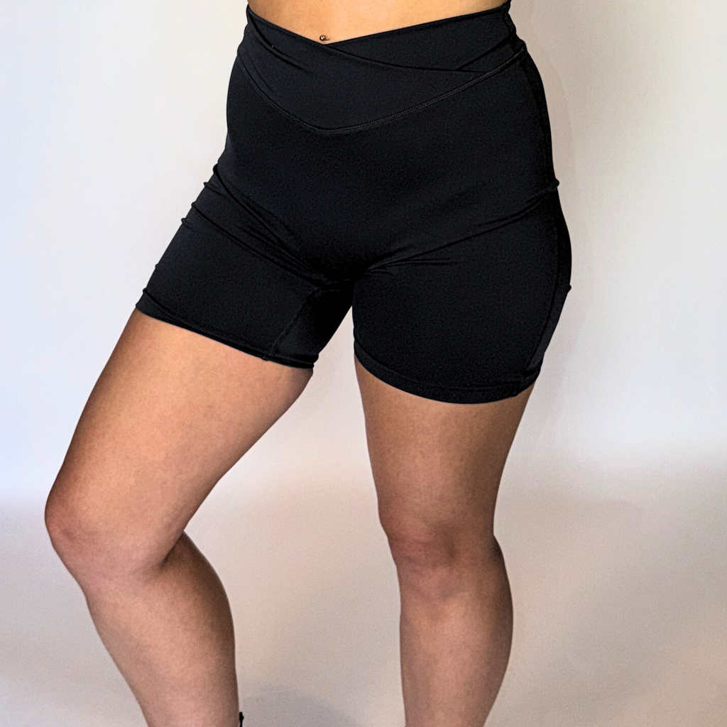 Black athletic shorts worn by a person on a plain background